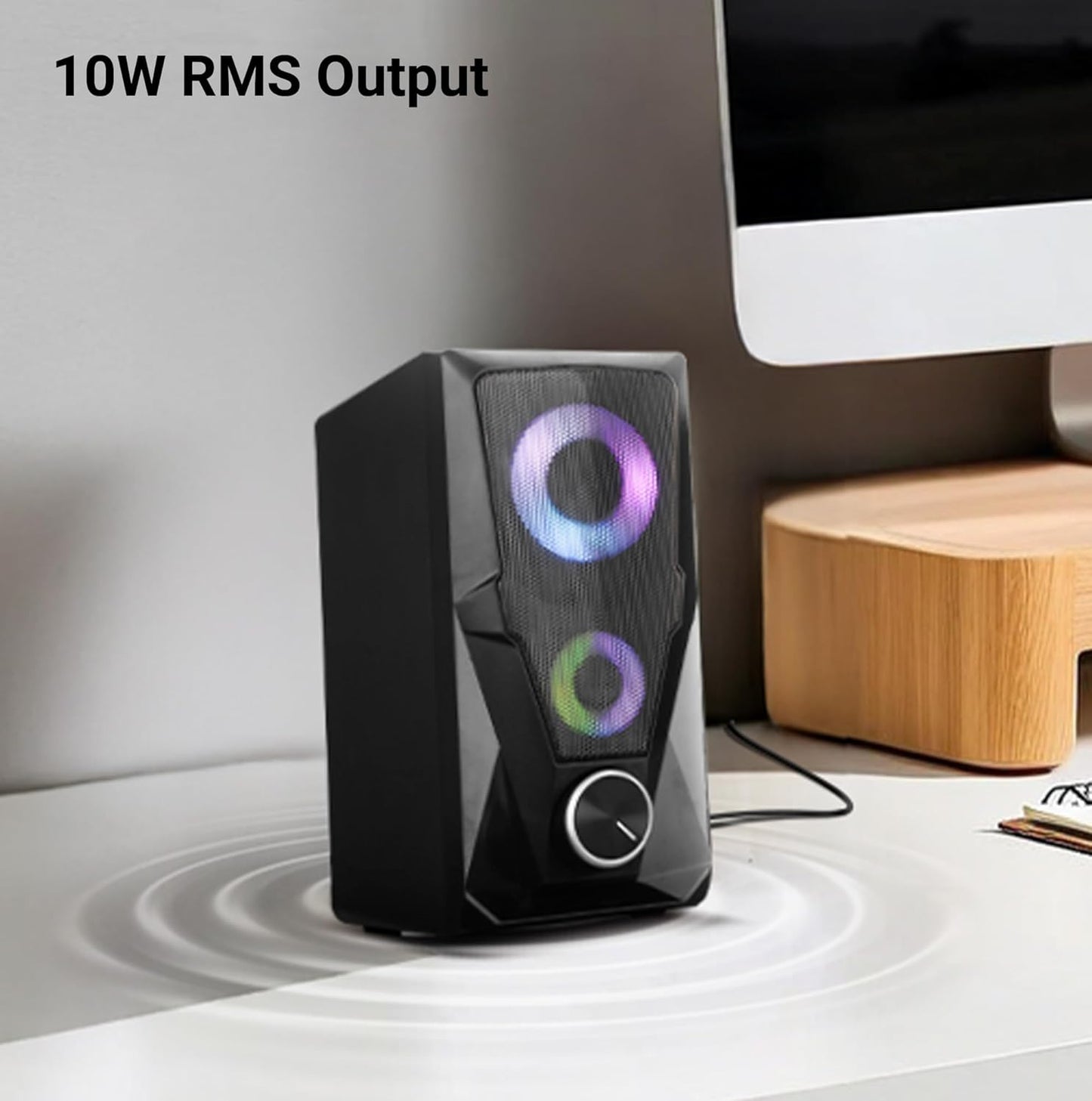 Black speaker with RGB lighting on a desk next to a computer monitor, displaying 10W RMS output.